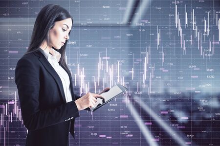 Portrait of attractive thoughtful young european businesswoman using tablet in blurry office...
