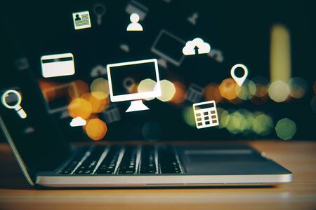 Side view and close up of notebook with glowing media icons on bokeh desktop background. Technology and ai concept. Double exposureの写真素材