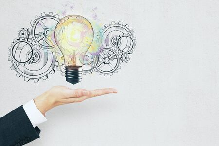 Hand holding light bulb with gears. Success and idea conceptの写真素材