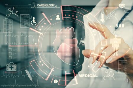 Cardiology and science concept. Doctor hand using creative glowing medical interface hud hologram on blurry hospital interior background. Multiexposureの写真素材