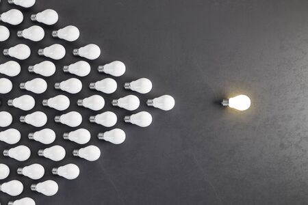 Glowing light bulb and many light bulbs in form of an arrow on gray background. Leadership and Idea...