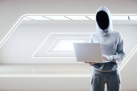 Hacker using laptop in white futuristic gallery interior with abstract light window. Innovation and modern concept.の写真素材