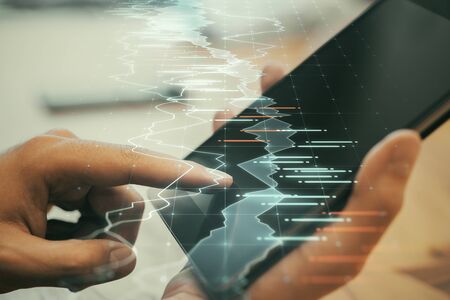 Hand using tablet with abstract forex chart hologram. Analytics and trade concept.の写真素材