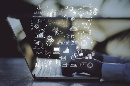 Hand using laptop on desktop with abstract business plan hologram on blurry background. Analytics and trade concept.の写真素材