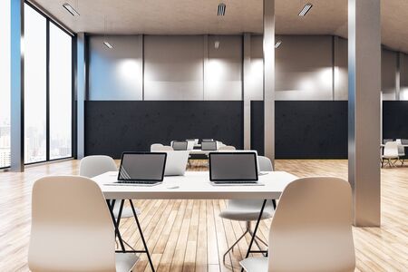 Minimalistic coworking office interior with laptops on desktop, other pieces of furniture and...