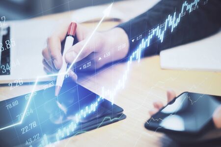 Hand with pen using tablet and abstract chart hologram on blurry background. Analytics and trade...