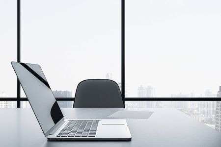 Bright office interior with panoramic city view and  laptop on desktop. 3D Renderingの写真素材