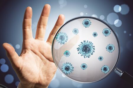 Hand and virus through a magnifying glass. Coronavirus crisis and search concept.の写真素材