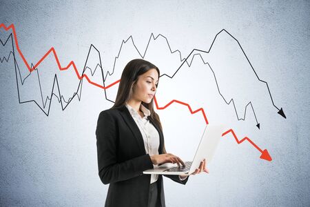 Businesswoman using laptop and crash crisis chart with falling red arrow. Business and financial crisis concept. Multiexposureの写真素材