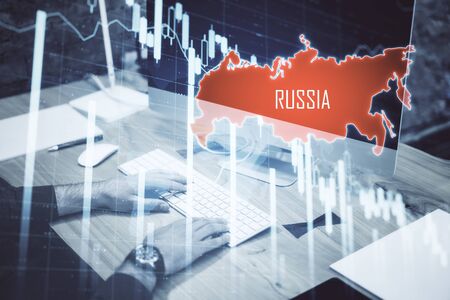 Side view of hand using keyboard on desktop with  map of Russia and creative crash recession chart with arrow. Business and financial crisis concept. Double exposureの写真素材