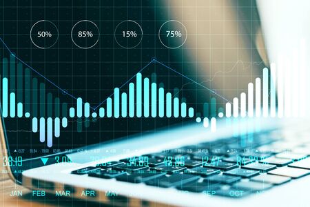 Laptop with creative chart and business analytics on blurry desktop. Finance and trade concept....