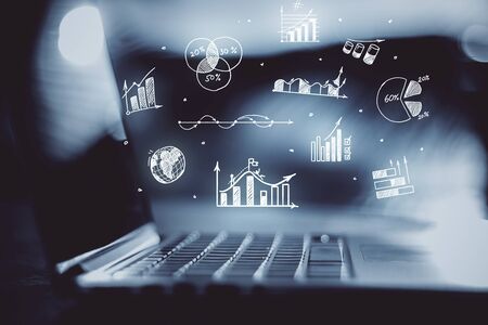 Laptop with charts and graphs on blurred office desktop. Success and startup concept.の写真素材