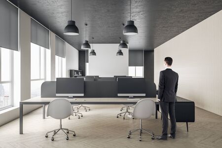 Businessman standing in modern coworking office hall with computers and city view.  Occupation and...