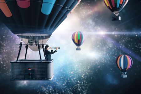 Young businesswoman in air balloon with telescope flies in space. Business and research concept.の写真素材