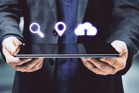 Businessman holding digital tablet with blank screen and digital icons. Technology and innovation...