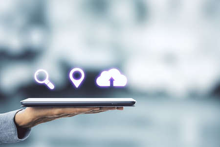 Hand holding digital tablet with digital web communication icons on blurry background. Technology and innovation concept.の写真素材