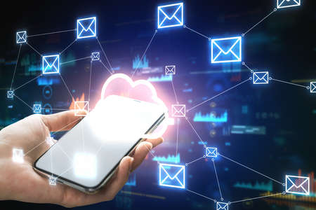 Hand holding smartphone with glowing cloud icon interface on blurry office background with email...