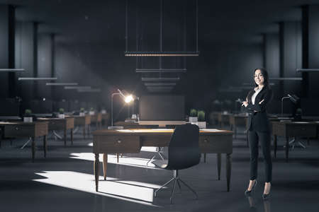 Businesswoman standing in coworking hight office interior with computers and furniture. Occupation and worker concept.の写真素材