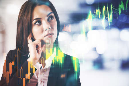Thinking businesswoman and stock chart hologram on digital screen. Money and trade concept. Double exposureの写真素材