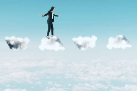 Businesswoman in suit standing on clouds on city background. Business and challenge concept.