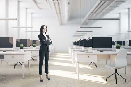 Businesswoman standing in coworking office with computers and furniture. Occupation and worker concept.の写真素材