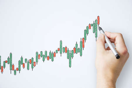 Businessman hand with pen drawing creative color candlestick chart on white wall. Increase and stats...