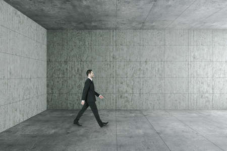 Businessman walking in concrete interior with empty copyspace on wall. Gallery concept. Mock up,の写真素材
