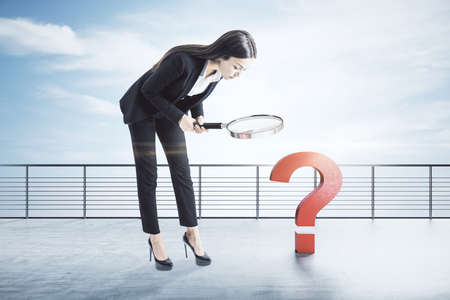 Young european businesswoman with magnifying glass search drawing question mark. Confusion and...
