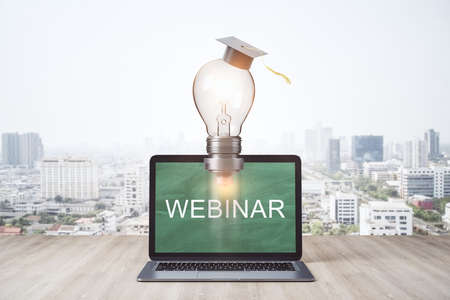 Rocket lamp in graduate cap and laptop on wooden table. Webinar and education concept. 3D Rendering