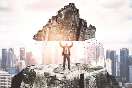 Businessman standing on mountain top and holding rock over head on city background. Leadership and...