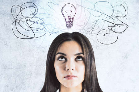 Young businesswoman looking on drawing light bulbs over head. Success and startup concept.