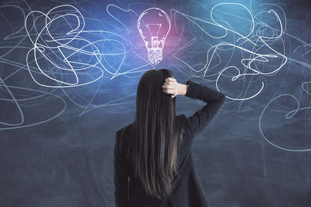 Businesswoman in suit looking on drawing light bulb blackboard. Brainstorm and innovation concept