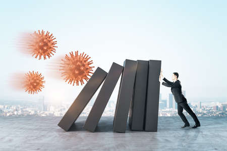 Businessman holds concrete blocks in which red coronavirus virus is removed on city background. Coronavirus and challenge concept.の写真素材