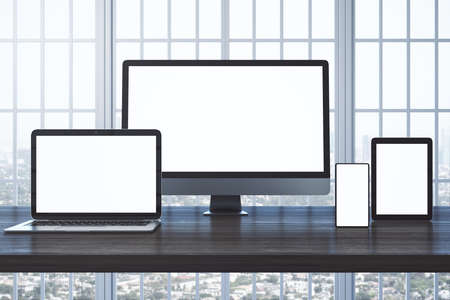 Tablet, smartphone, computer monitor and laptop with blank screen on table. Technology and...
