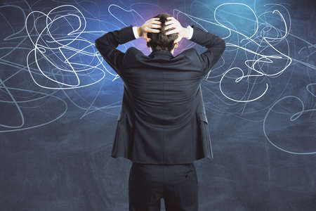 Thoughtful young businessman and drawing abstract lines on blackboard. Business and education concept.の写真素材