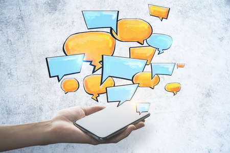 Cellphone with color speech bubble on concrete wall background. Social media, communication and...