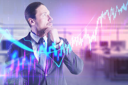 Young businessman thinking with glowing stock chart and marketing data. Finance and trade concept.