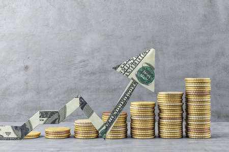Growing chart of gold coins with dollar arrow banknote on concrete wall background. Trade and...