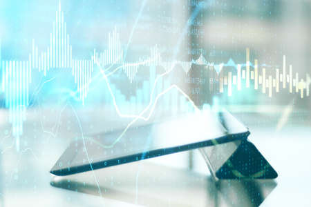 Digital tablet computer on desktop with glowing stock chart hologram on blurry office background....
