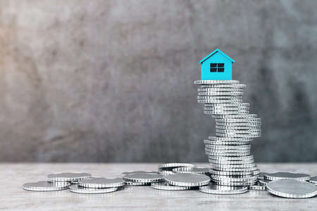 Blue house on silver coins heap in concrete interior. Finance and real estate concept. 3D Renderingの写真素材