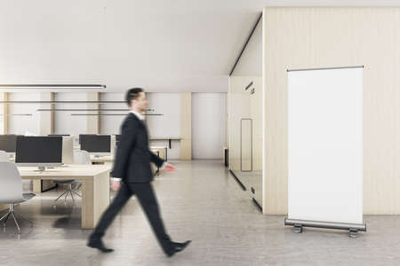 Businessman walking in loft coworking office interior with furniture and blank poster on wall. 3D...