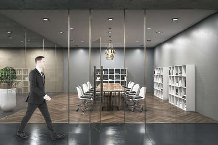 Businessman walking in business conference room interior with large meeting table. Workplace and...