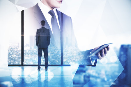 Businessman using tablet computer and looking to window on skyscraper background. Teamwork and communication concept. Multiexposureの写真素材