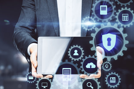 Businessman holding tablet with digital cogs interface and communication icons. Technology and innovation concept. Close upの写真素材