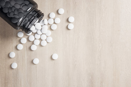 White pills spilled out of bottle on wooden table. Medicine and illness concept. Close up, 3D Renderingの写真素材