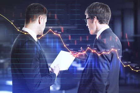Businesspeople looking in document and glowing falling forex chart on virtual screen. Teamwork and...