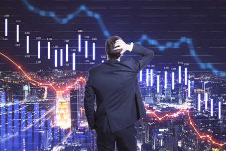 Scared businessman looking on falling stock market statistics hologram. Business and financial crisis concept. Multiexposureの写真素材