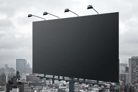 Huge blank black outdoor billboard with lights on top at city background. Mockup. 3D renderingの写真素材