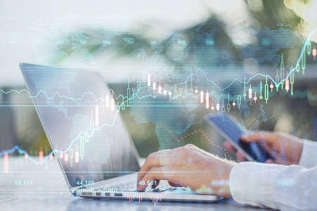 Online investment concept: digital screen with stock market diagram and graphs and man using laptop...