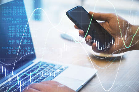 Global investment market concept with man hands with modern cell phone and laptop and abstract...